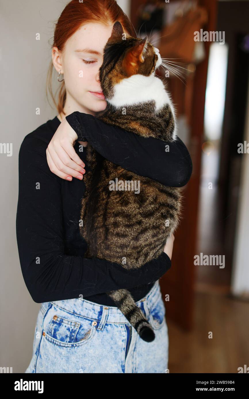Photo d'intérieur d'une dame incroyable tenant un animal de compagnie. Portrait de femme tenant le chat rayé mignon avec les yeux verts. Banque D'Images