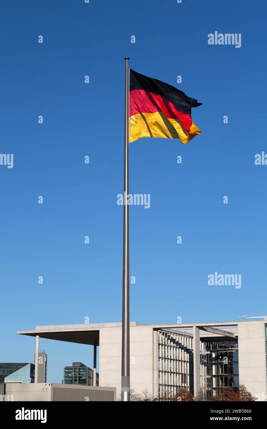 Drapeau allemand sur un mât contre le ciel bleu, drapeau national de l'Allemagne. Banque D'Images