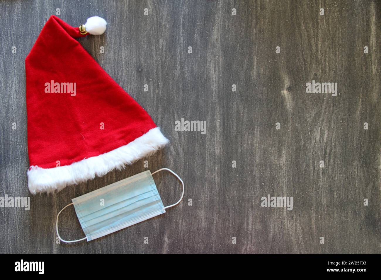 Chapeau de Père Noël et masque de protection à usage clinique sur fond gris vintage Banque D'Images