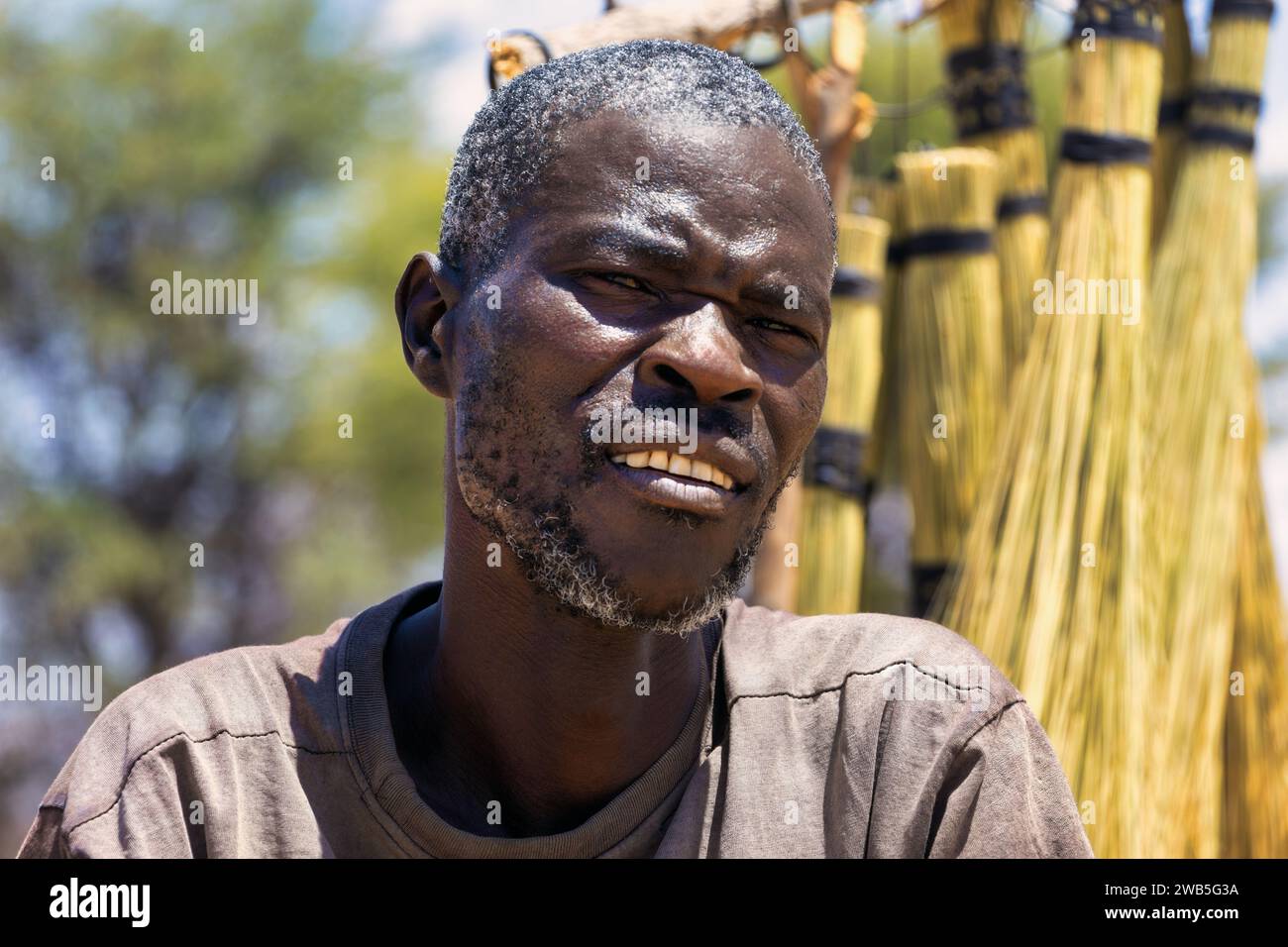 portrait d'un bel homme africain d'âge moyen avec des traits masculins, debout à l'extérieur vendant des balais sur le bord de la route Banque D'Images