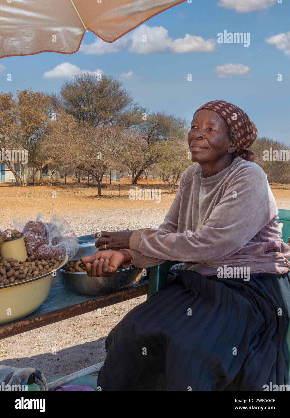 vendeur de rue africain vendant des cacahuètes, vieille femme entrepreneure à une intersection Banque D'Images