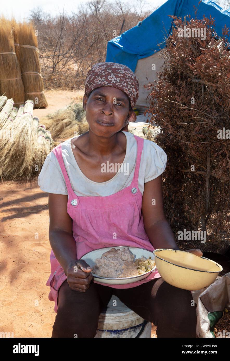 Femme africaine , heure du déjeuner dans le village , cabane , cuisine en plein air , camp de travail coupant l'herbe de chaume , manger pap pour la pause déjeuner, de manière traditionnelle, Banque D'Images