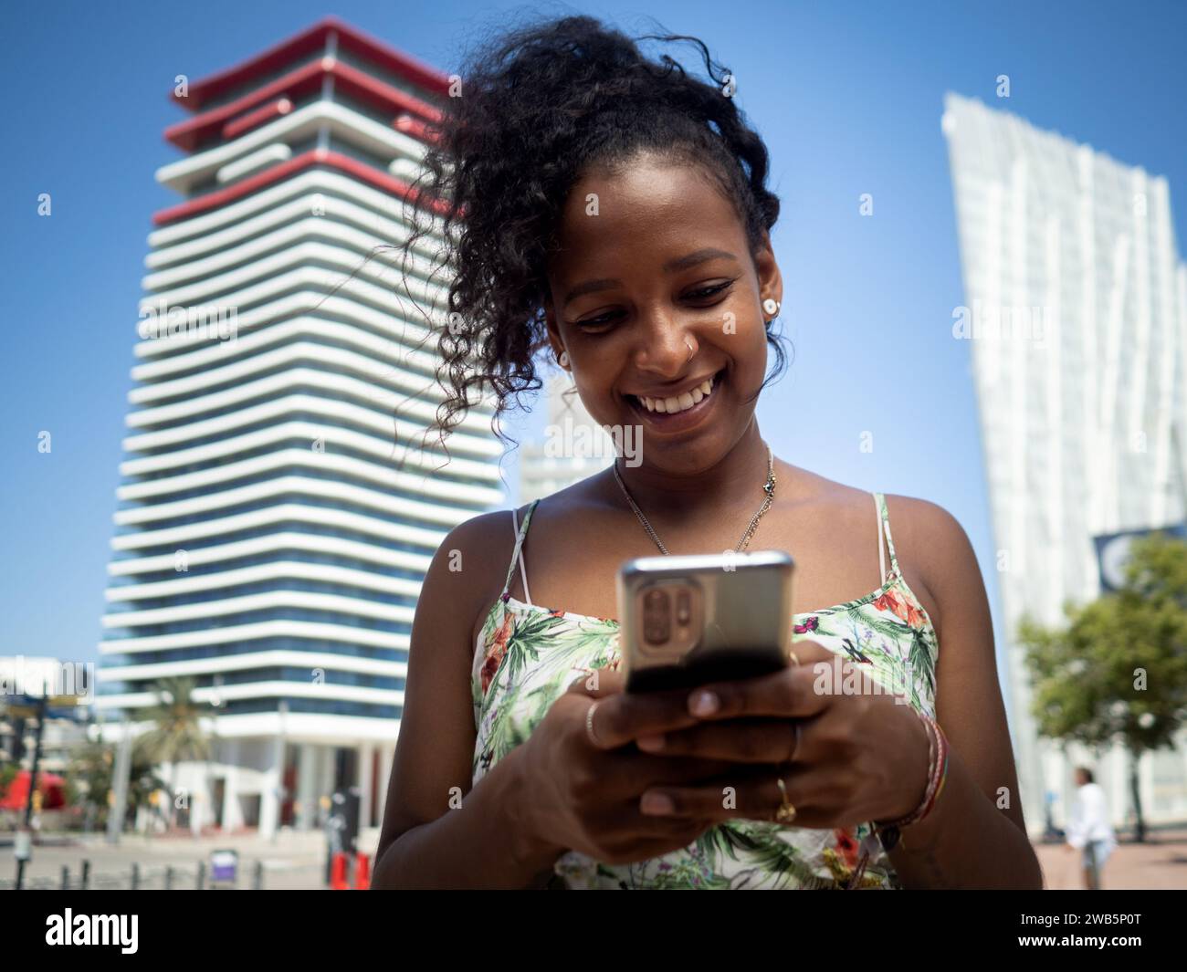 Jeune femme afro-américaine insouciante bavardant dans une ville en été Banque D'Images