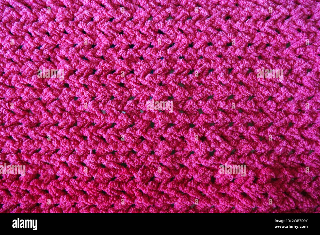 Textures de ce gros plan d'une couverture crochetée rose. Banque D'Images