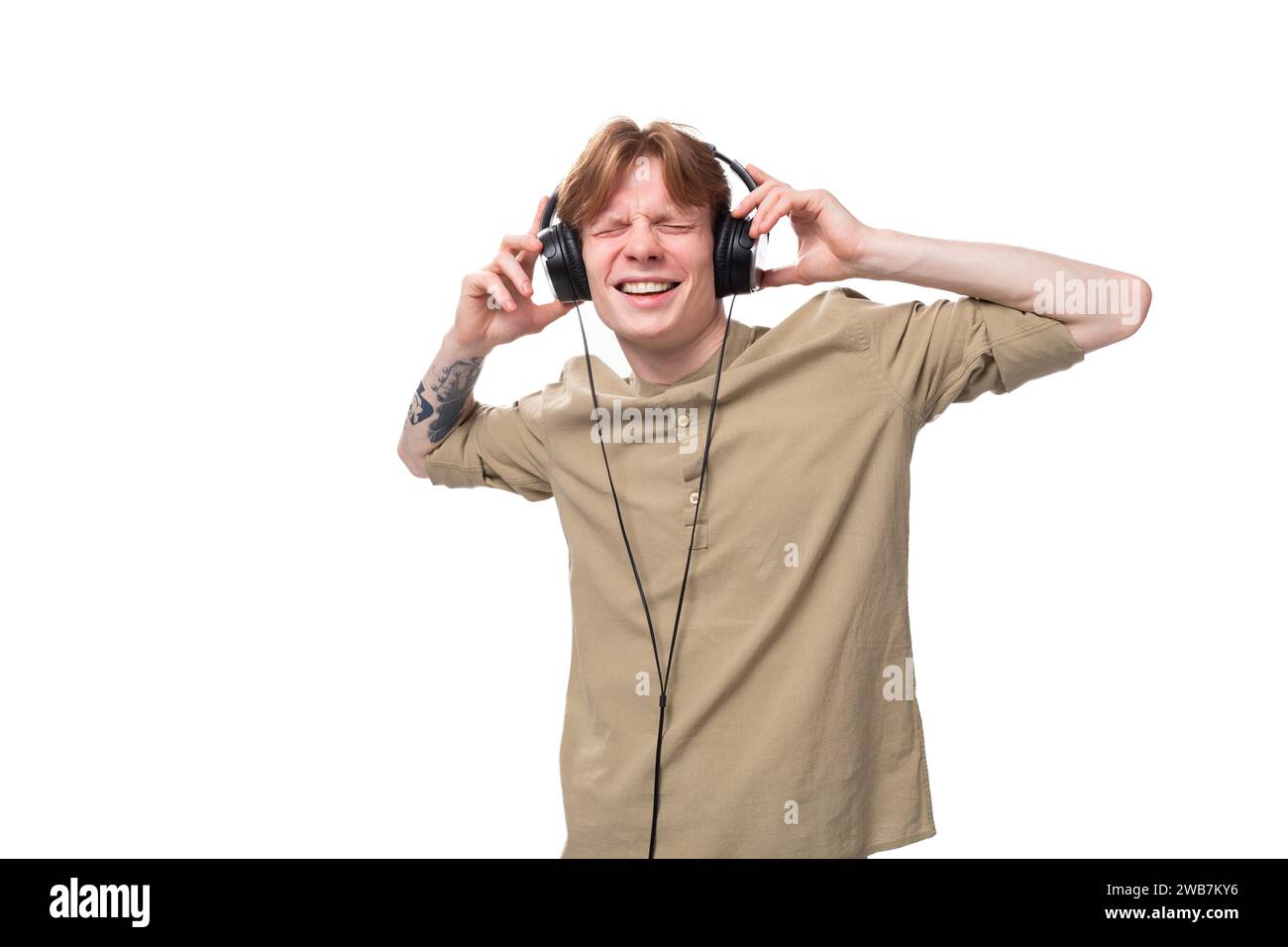 jeune mec caucasien mignon avec les cheveux rouges dansant à la musique dans les écouteurs Banque D'Images