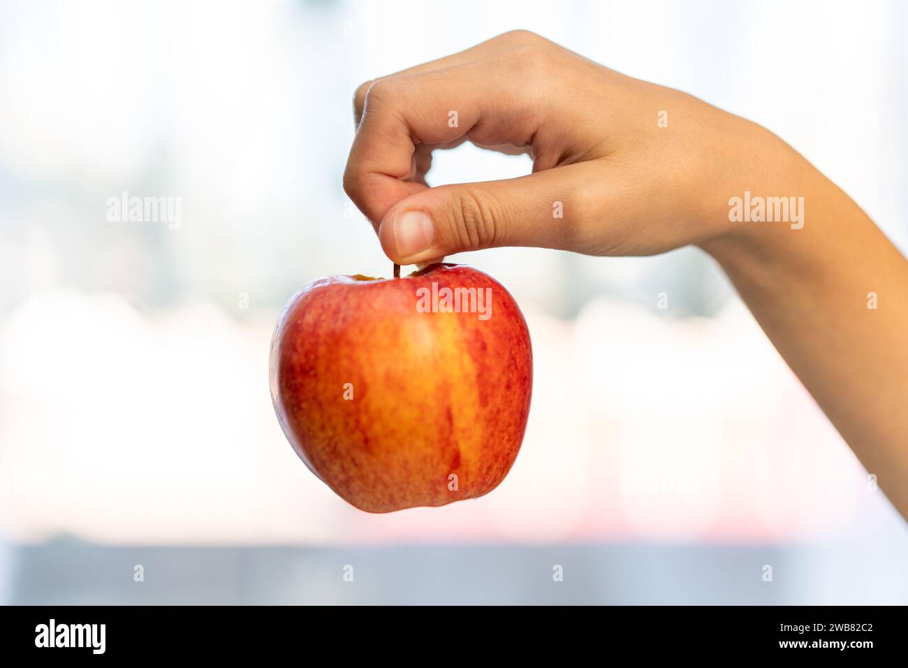 Gros plan photo studio d'une main femelle tenant une pomme fraîche. sur fond blanc. Pomme rouge. Banque D'Images