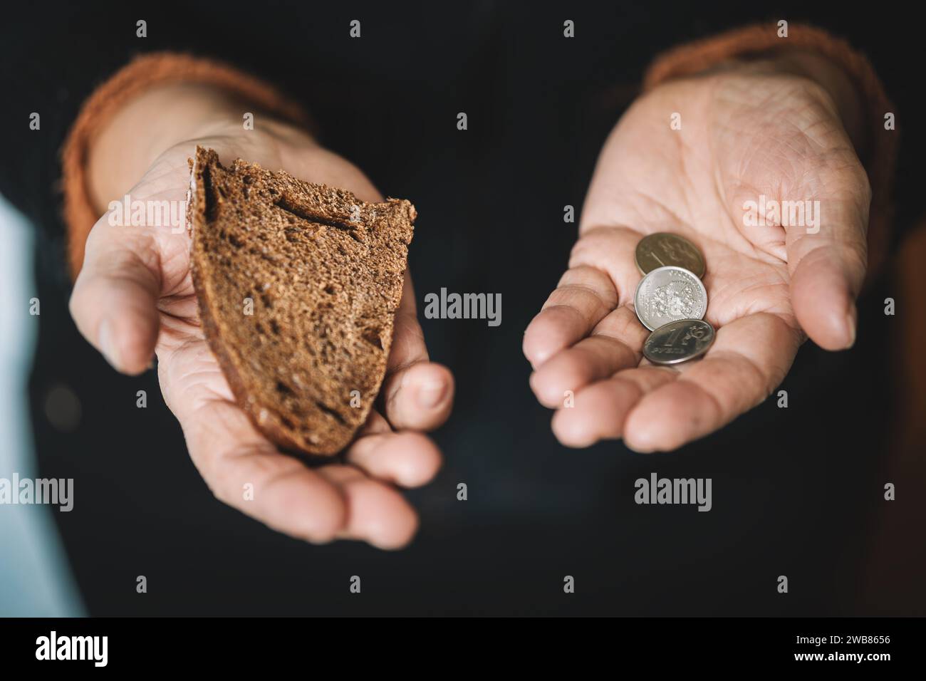 Femme affamée tenant de l'argent et du pain sur un fond noir, les mains avec de la nourriture gros plan. De l'argent dans les mains sales d'une pauvre femme affamée sur un dos sombre Banque D'Images
