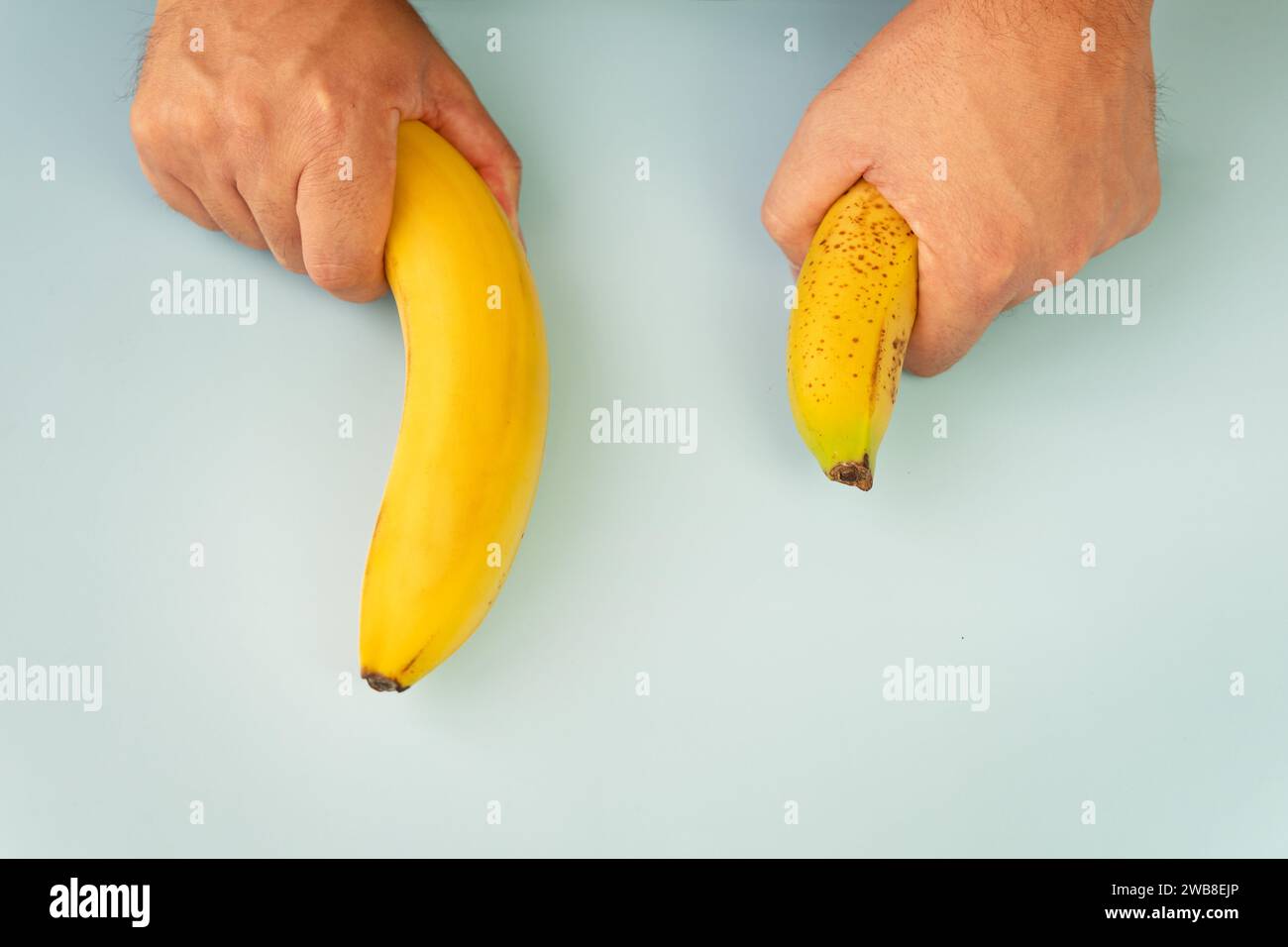 Petite banane comparer taille Wish banane sur fond bleu. Libido de vie sexuelle, taille du pénis et concept de puissance. Pose à plat, vue de dessus, espace de copie Banque D'Images