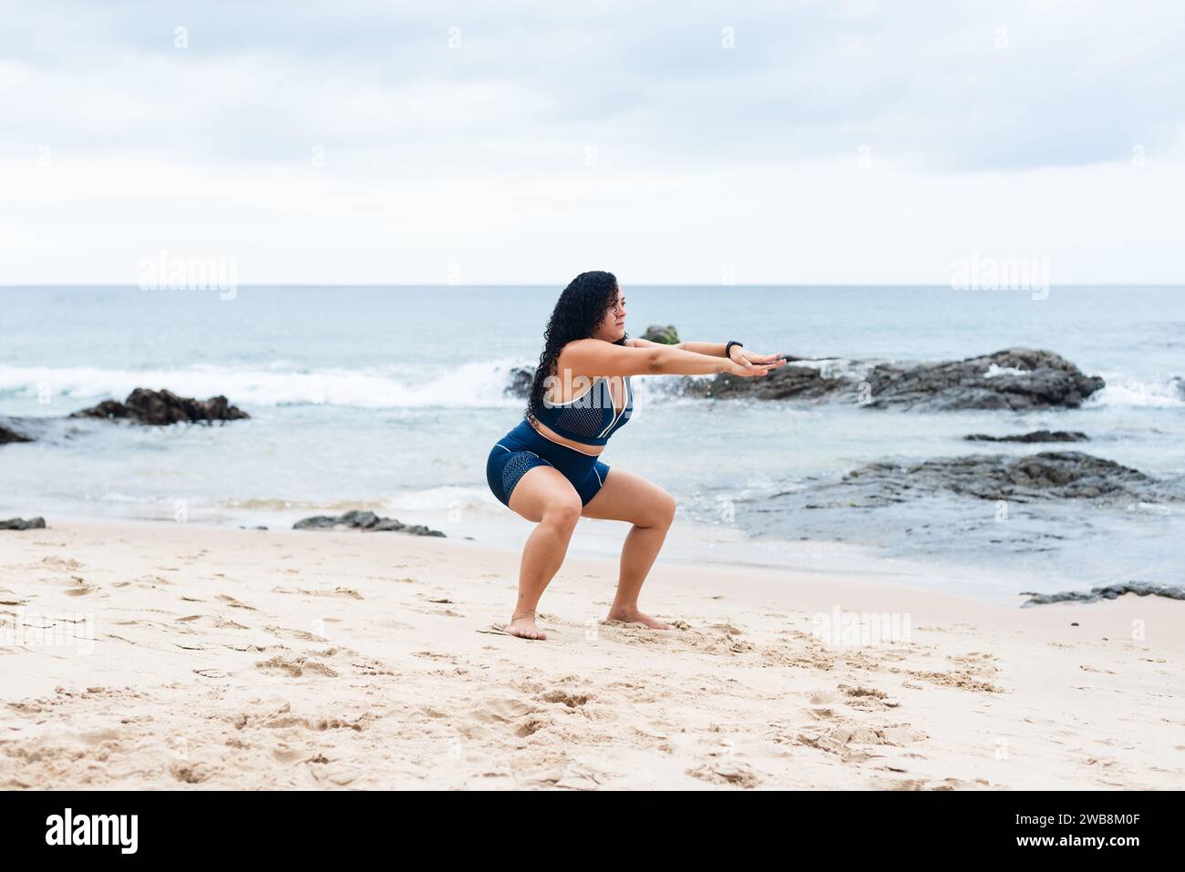 Portrait de belle femme de fitness faisant des étirements sur le sable de plage. Mode de vie sain. Banque D'Images