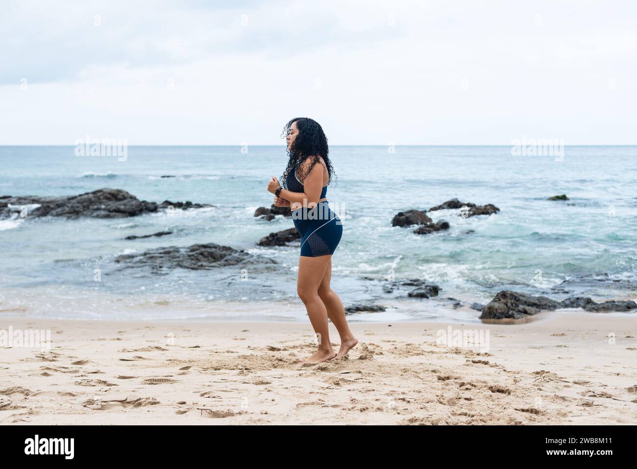 Portrait de belle femme de fitness faisant des étirements sur le sable de plage. Mode de vie sain. Banque D'Images