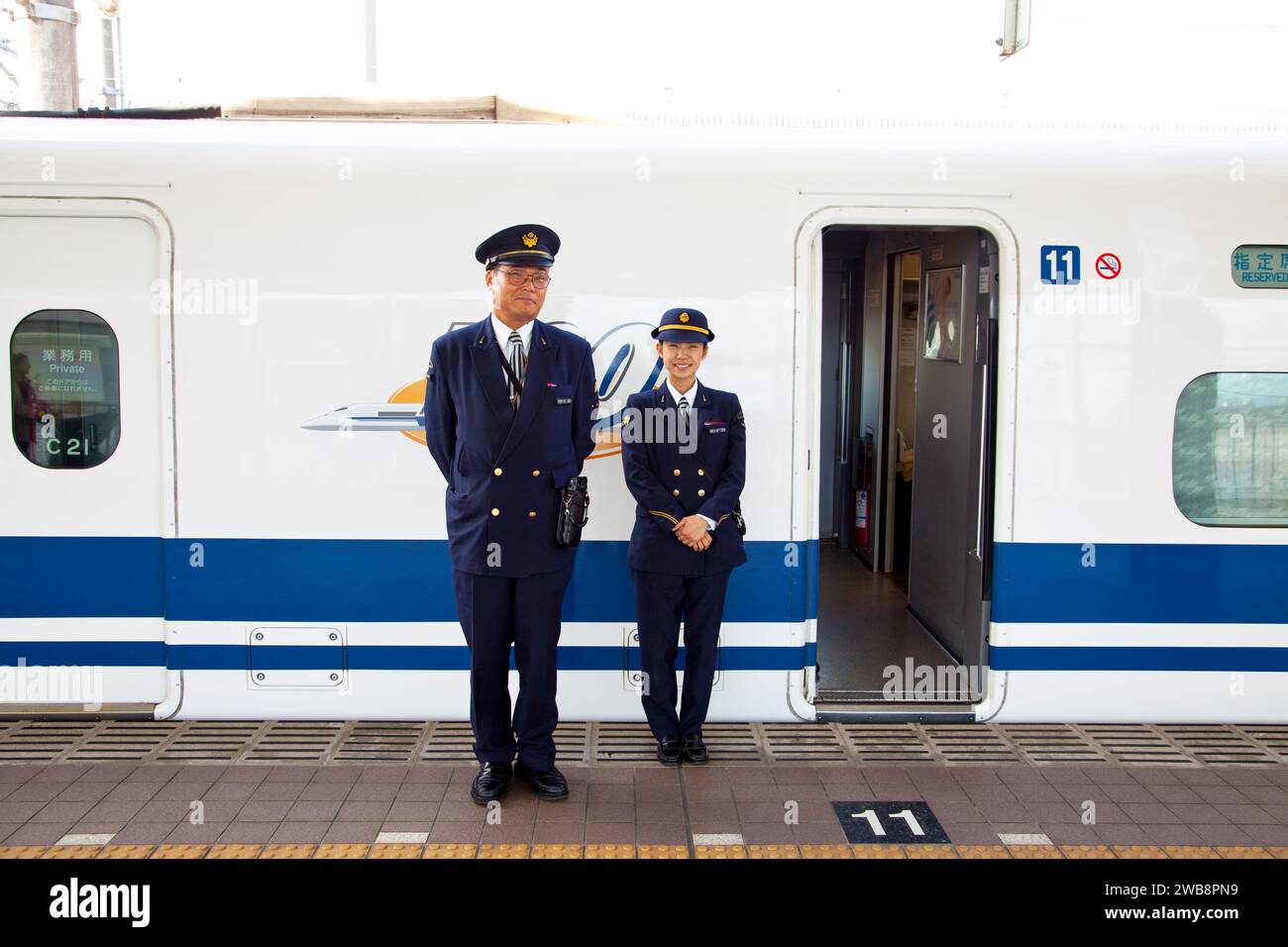 Shinkansen N700 Series à une gare avec deux membres du personnel en uniforme à côté du train. Banque D'Images