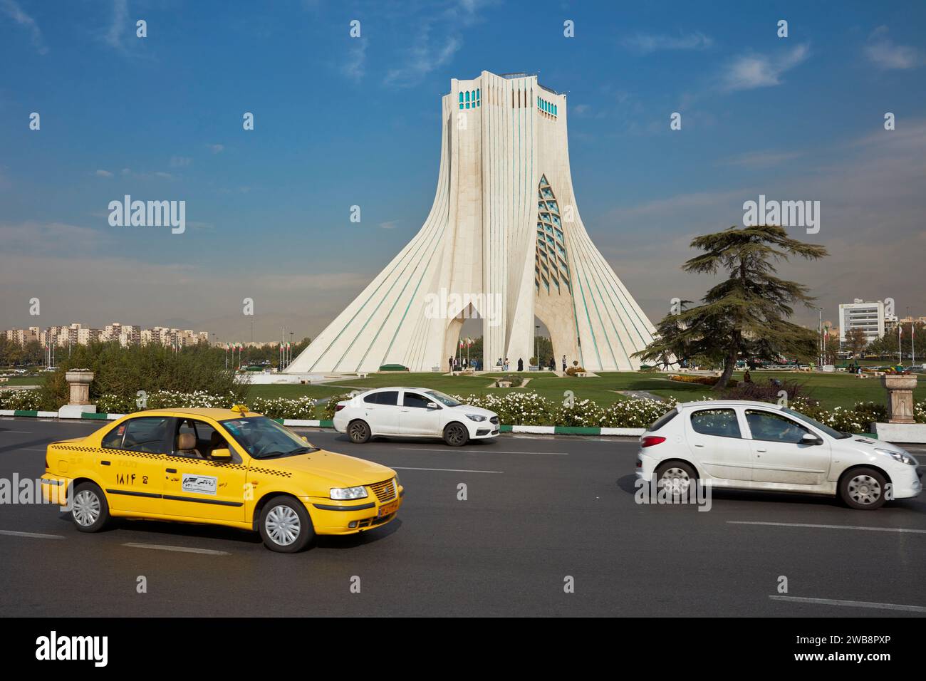 Voitures passant devant la tour Azadi (Tour de la liberté), un monument emblématique de Téhéran, Iran. Banque D'Images