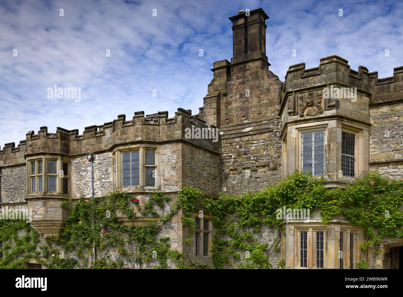 Peak District, Bakewell, Derbyshire, Angleterre, Royaume-Uni - Maison seigneuriale médiévale Haddon Hall avec murs crénelés, baies vitrées et cheminées Banque D'Images