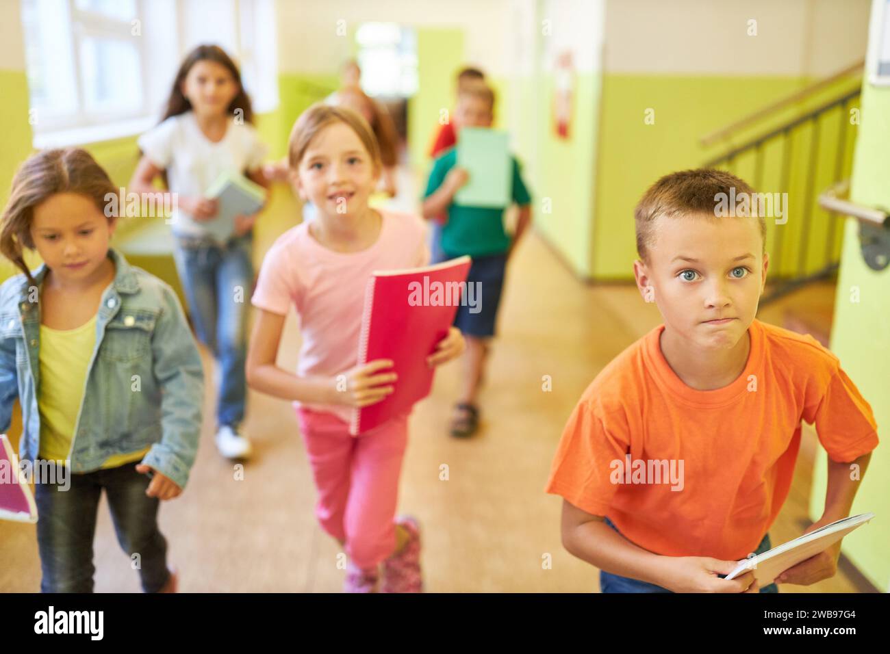 Heureux enfants masculins et féminins courant dans le couloir de l'école pendant la récréation Banque D'Images