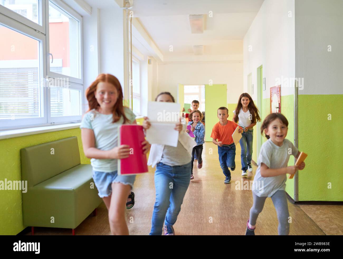 Groupe d'enfants heureux de l'école primaire courant dans le couloir à l'école Banque D'Images