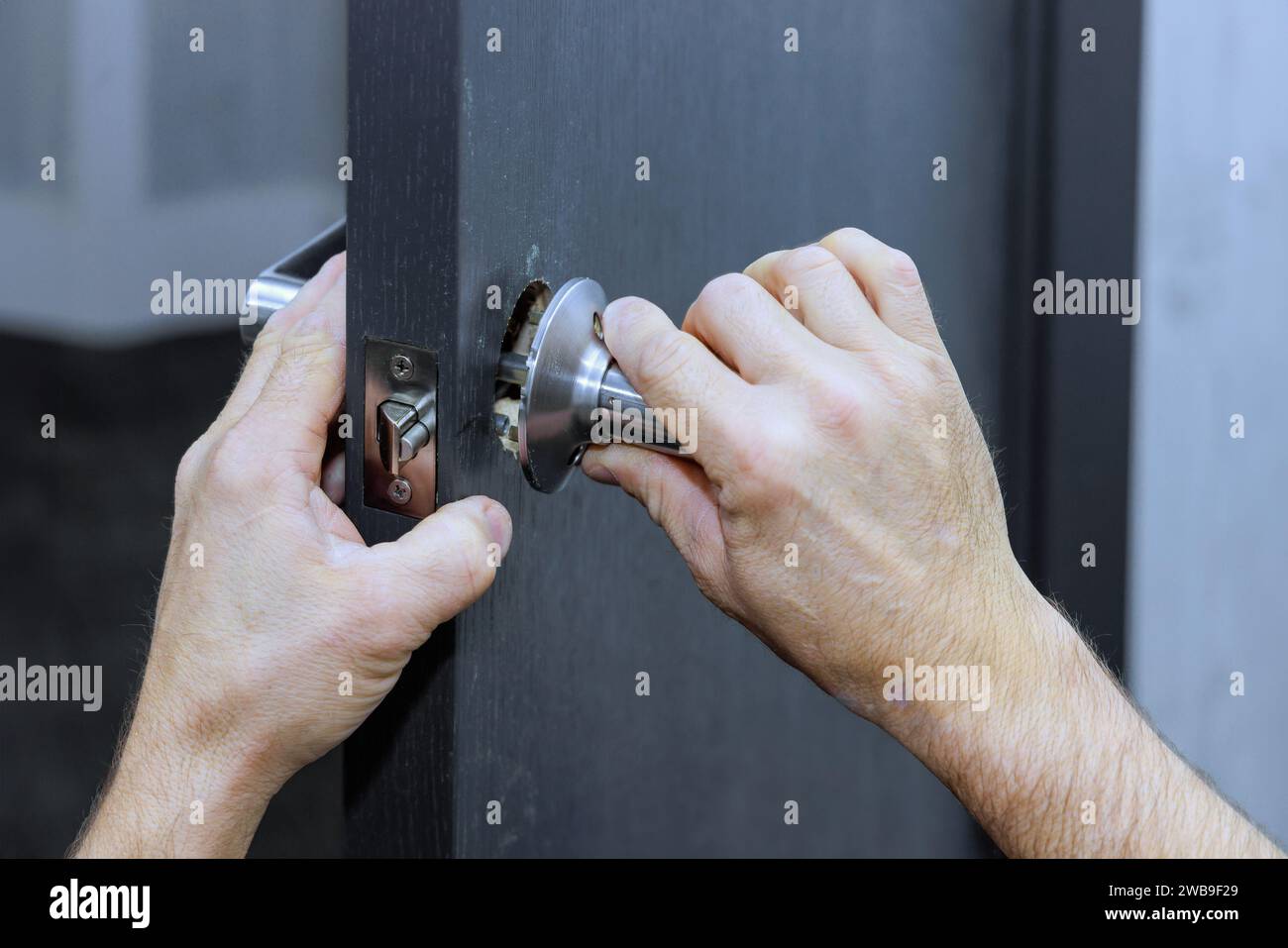Les poignées de verrouillage sont installées sur la porte de la chambre par le charpentier Banque D'Images