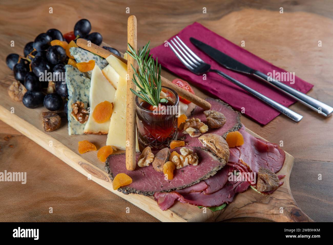 Plat d'apéritifs avec viande fumée, fromage cheddar et raisins noirs Banque D'Images