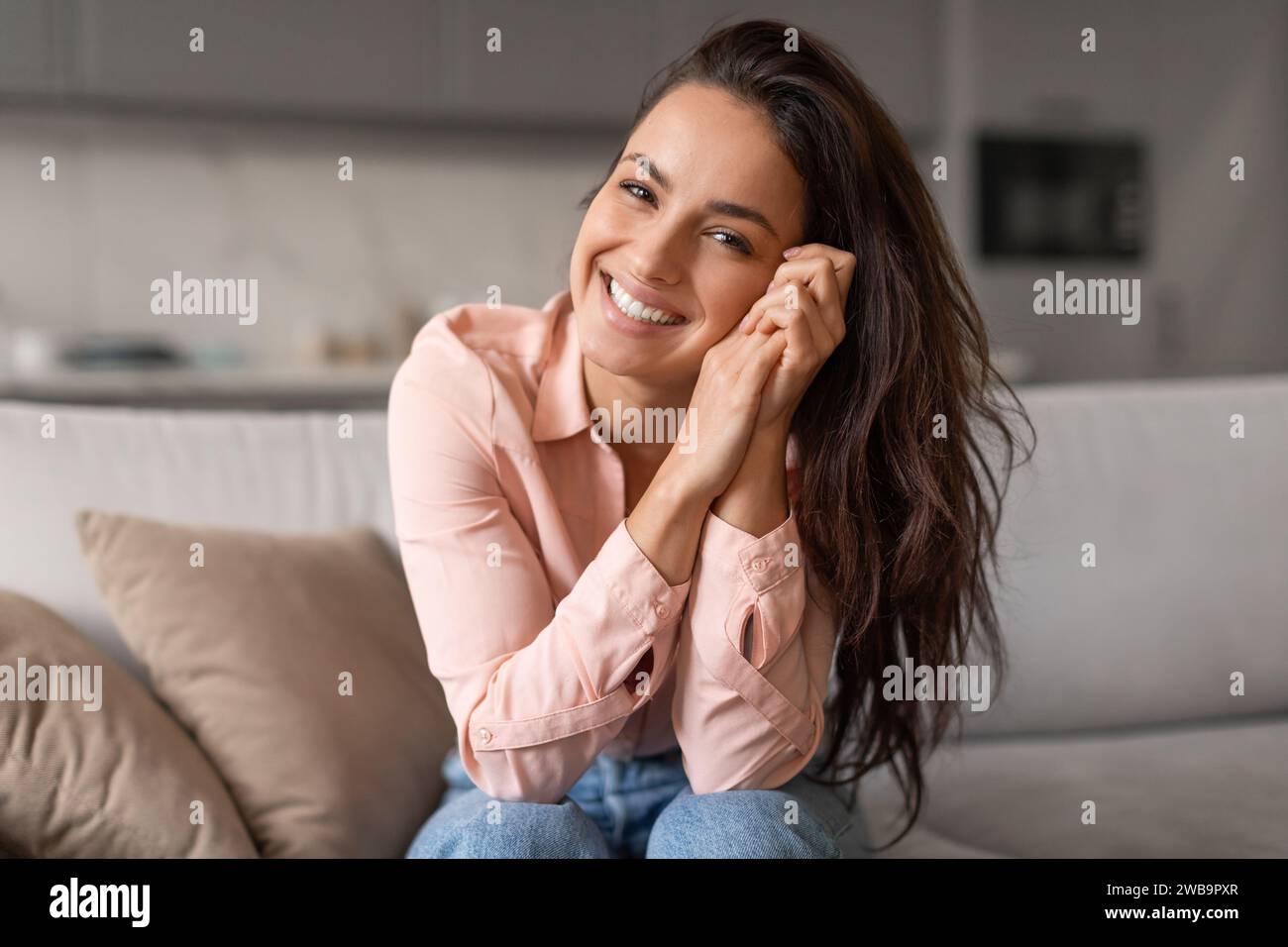 Jeune femme souriante posant avec désinvolture les mains sur le visage Banque D'Images