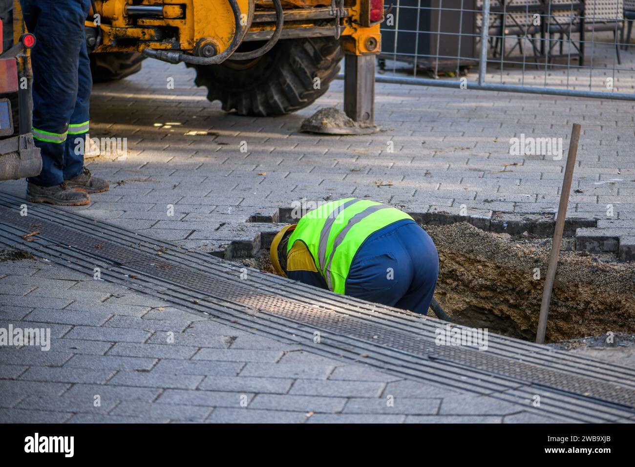 Travailleurs d'entretien sur le site réparant la conduite d'eau endommagée sous le trottoir de la rue, focalisation sélective Banque D'Images