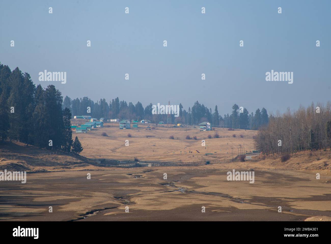 Un homme marche sur le lac d'eau asséchée à la célèbre station touristique Yusmarg à Budgam au nord-est de Srinagar Cachemire. La vallée du Cachemire est une destination touristique hivernale mondialement connue en raison de ses stations de ski et de ses montagnes. Cependant, la région connaît actuellement une sécheresse exceptionnelle, avec un manque de précipitations de 79 % entre décembre 2023 et la première semaine de janvier, et aucune chute de neige. Les experts météorologiques associent l'absence de pluie et de neige à El Nino, un événement climatique naturel défini par un réchauffement anormal des eaux de l'océan Pacifique. À l'avenir, les scientifiques préviennent que la vallée pourrait voir plus de RE Banque D'Images