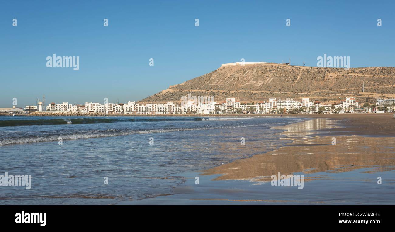 Agadir Plage et marée de l'océan Atlantique, avec Kasbah et Marina au loin Banque D'Images