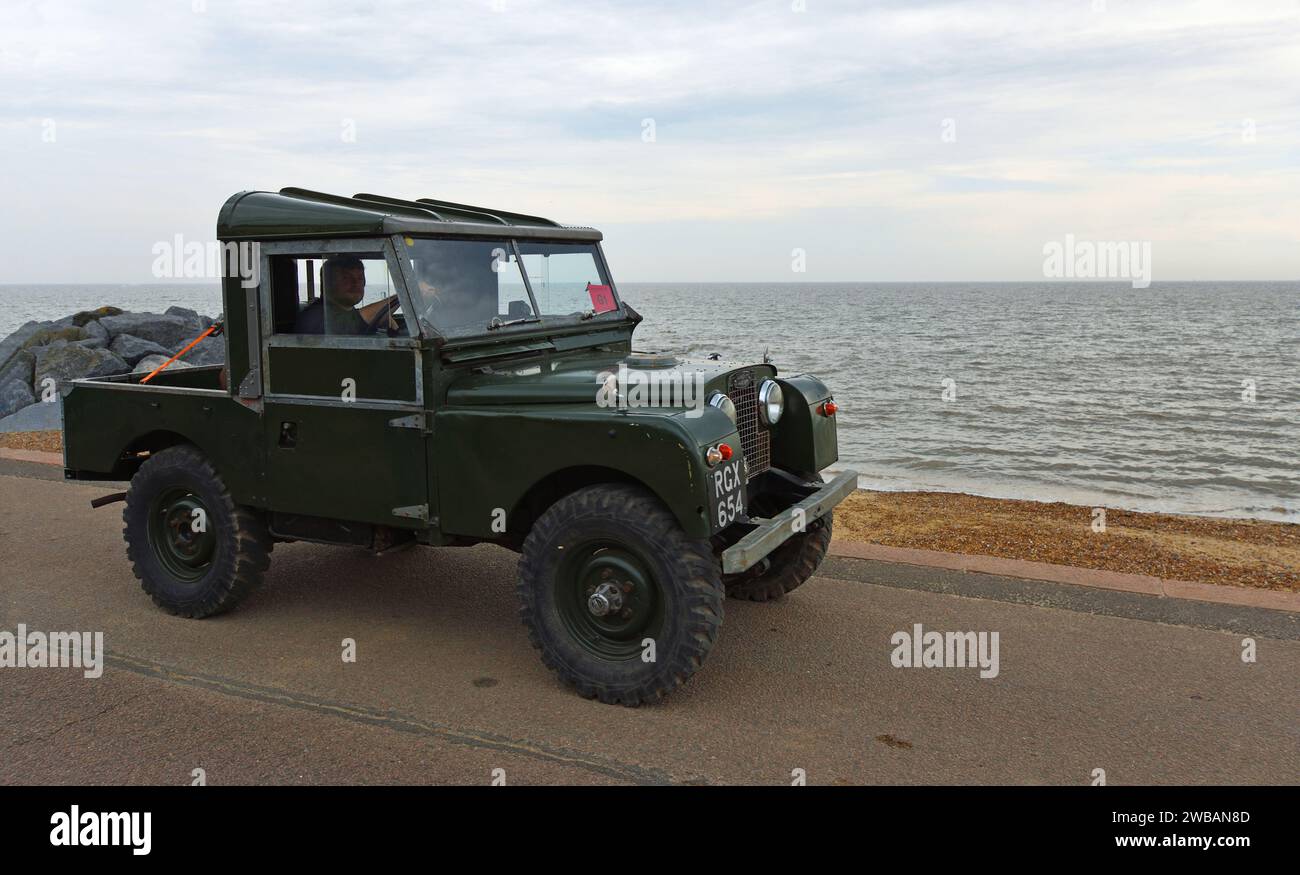 Land rover classique conduit sur la plage de promenade en bord de mer et la mer en arrière-plan. Banque D'Images
