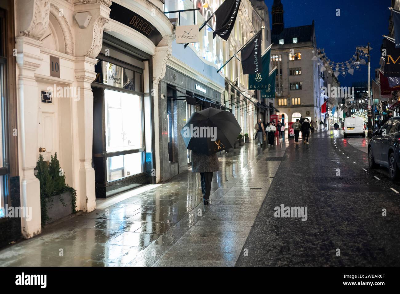 Les acheteurs bravent le froid hivernal pendant les averses glaciales et les averses de pluie sur Old Bond Street, la marque de créateurs de luxe de Londres Street, Angleterre, Royaume-Uni Banque D'Images