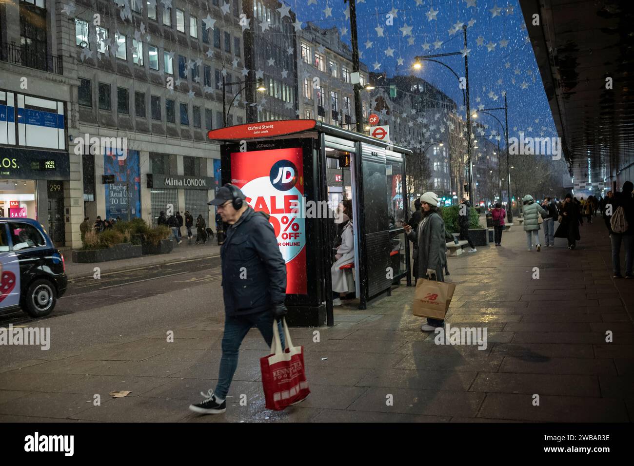 Les acheteurs bravent le froid hivernal pendant les averses glaciales et les averses de pluie sur Oxford Street, la rue la plus fréquentée de Londres, en Angleterre, au Royaume-Uni Banque D'Images