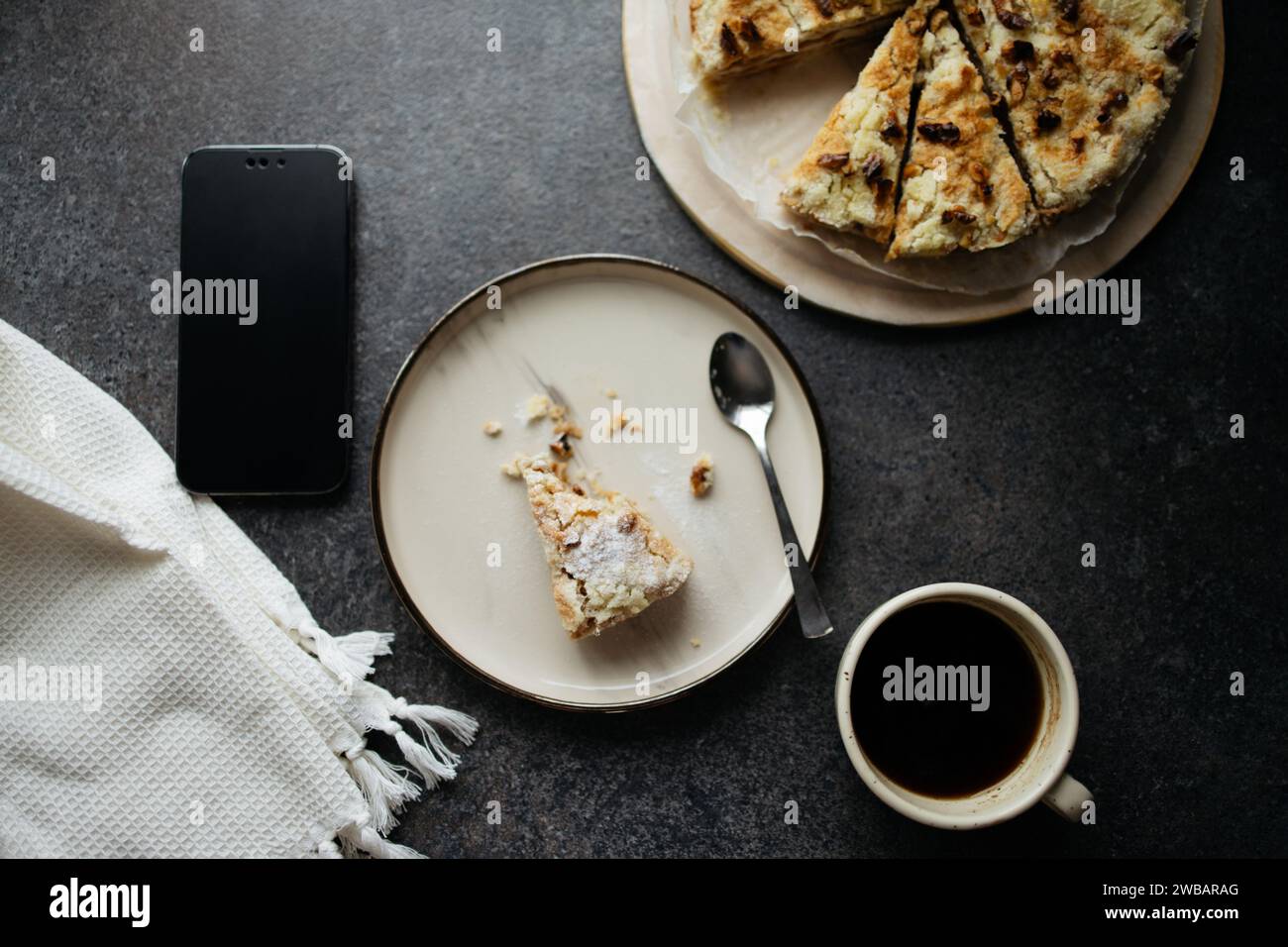 Prendre des repas avec smartphone. Vue de dessus de morceau de tarte mordu sur l'assiette, tarte entière et tasse de café noir Banque D'Images