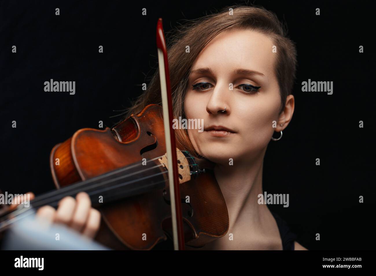 la violoniste, immergée dans sa musique, crée une atmosphère de solennité et de concentration, témoignage de son art. Banque D'Images