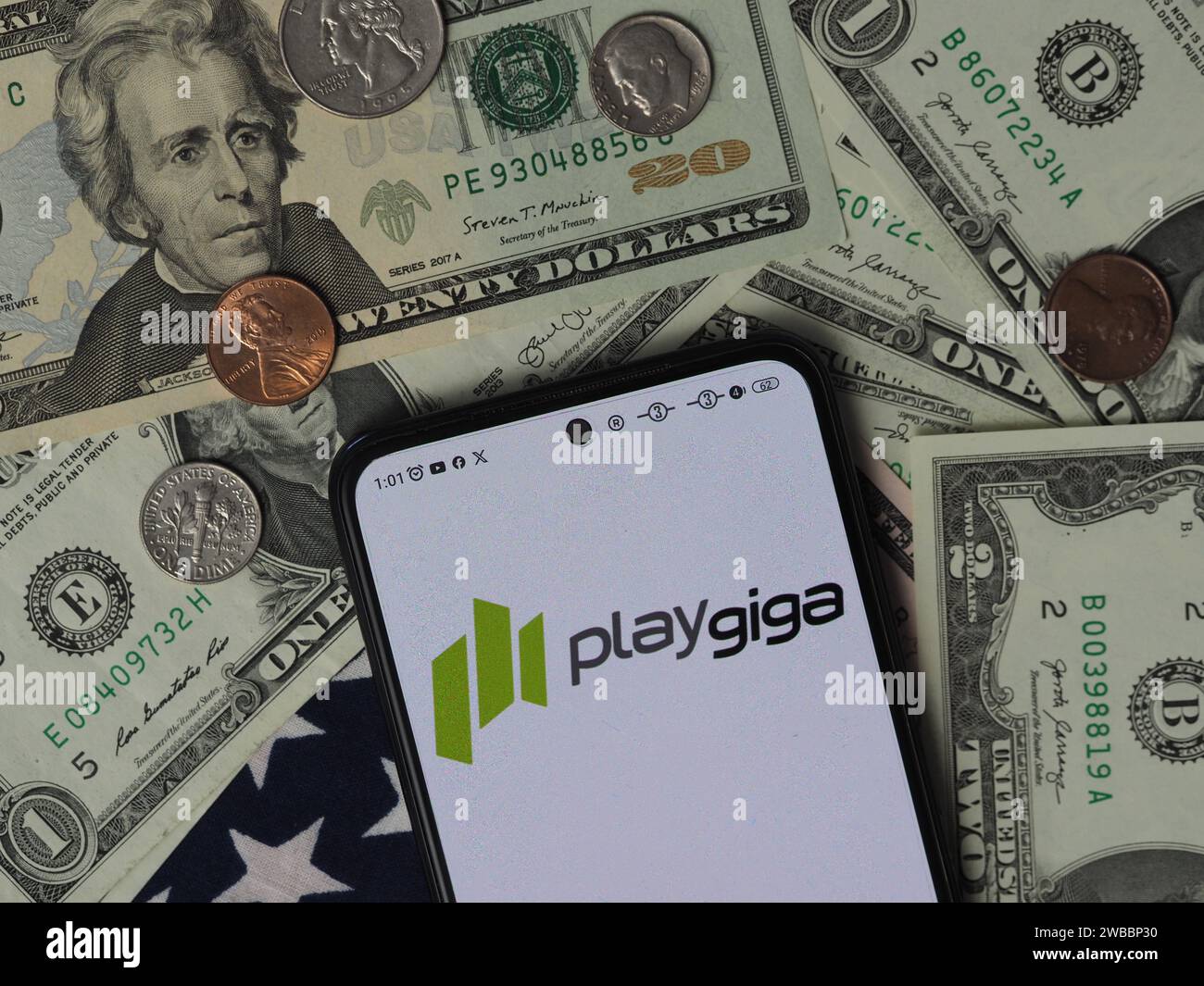 Bavière, Allemagne - 10 janvier 2024 : dans cette illustration photo, un logo PlayGiga S.L. vu affiché sur un smartphone avec des billets de dollar américain a Banque D'Images