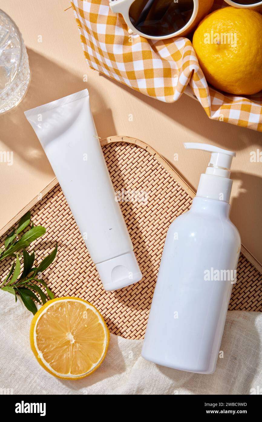 Scène de maquette pour la publicité et le produit cosmétique de marque de l'extrait de citron - tube en plastique blanc et bouteille de pompe sans marque sur fond beige avec le Banque D'Images