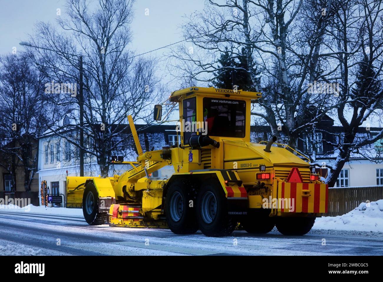 Niveleuse jaune Veekmas FG 2327 S enlevant la neige de la rue avec lame réglable après la chute de neige hivernale, vue arrière. Salo, Finlande. 29 décembre 20 Banque D'Images