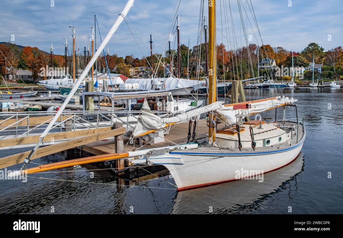 Petit voilier à un quai de la Nouvelle-Angleterre : un bateau avec des voiles à fourrure se trouve tranquillement près d'une jetée en bois un jour d'octobre à Camden, Maine. Banque D'Images