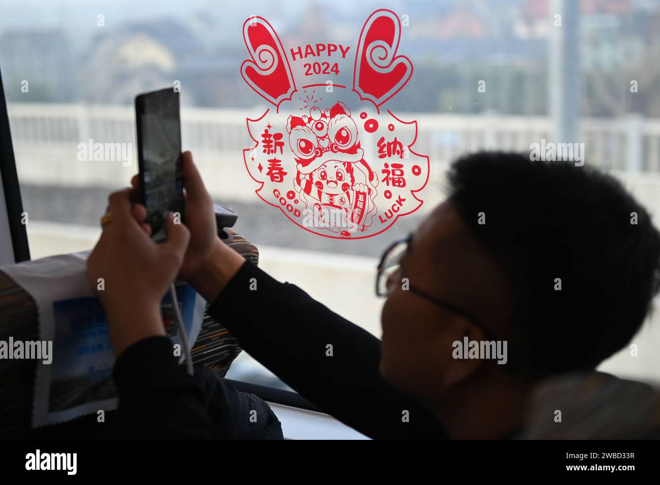 Hangzhou. 10 janvier 2024. Un passager est assis dans un train à grande vitesse se dirigeant directement vers la gare ferroviaire de Guangzhou est dans la province du Guangdong dans le sud de la Chine depuis la gare ferroviaire de Hangzhou Ouest dans la ville de Hangzhou dans la province du Zhejiang dans l'est de la Chine, le 10 janvier 2024. Un nouveau service de train de voyageurs reliant directement la gare de Hangzhou Ouest à Hangzhou et la gare de Guangzhou est à Guangzhou a été lancé mercredi. La Chine a commencé à mettre en œuvre un nouveau plan d'exploitation ferroviaire le même jour. Crédit : Huang Zongzhi/Xinhua/Alamy Live News Banque D'Images