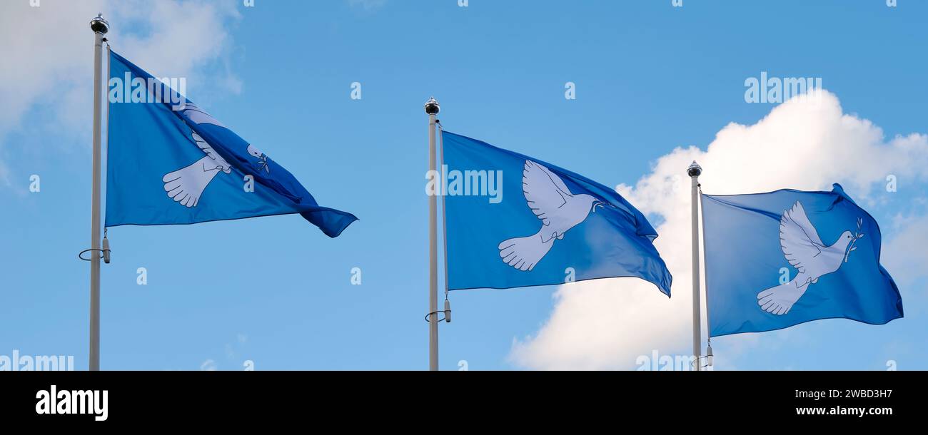 Trois drapeaux bleus de la paix dans une rangée imprimés avec une colombe avec une branche d'olivier dans son bec. La colombe à la branche est le symbole international de la paix. Banque D'Images