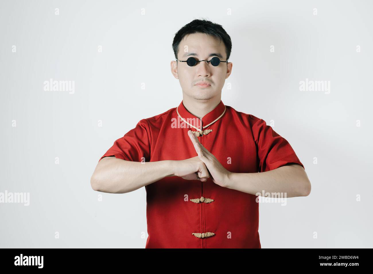 Homme asiatique portant un costume traditionnel avec geste de félicitations sur fond blanc. Concept du nouvel an chinois. Gong Xi Fa Cai. Banque D'Images