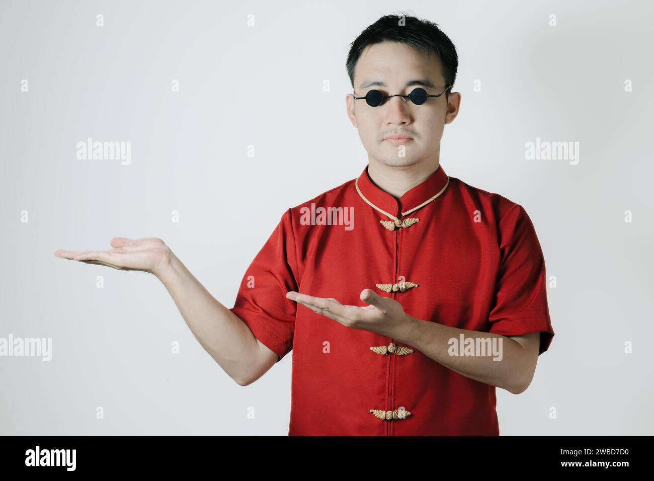 Homme asiatique portant un costume traditionnel ouvre sa main sur le côté gauche sur fond blanc. Bonne année chinoise. Gong Xi Fa Cai. Banque D'Images