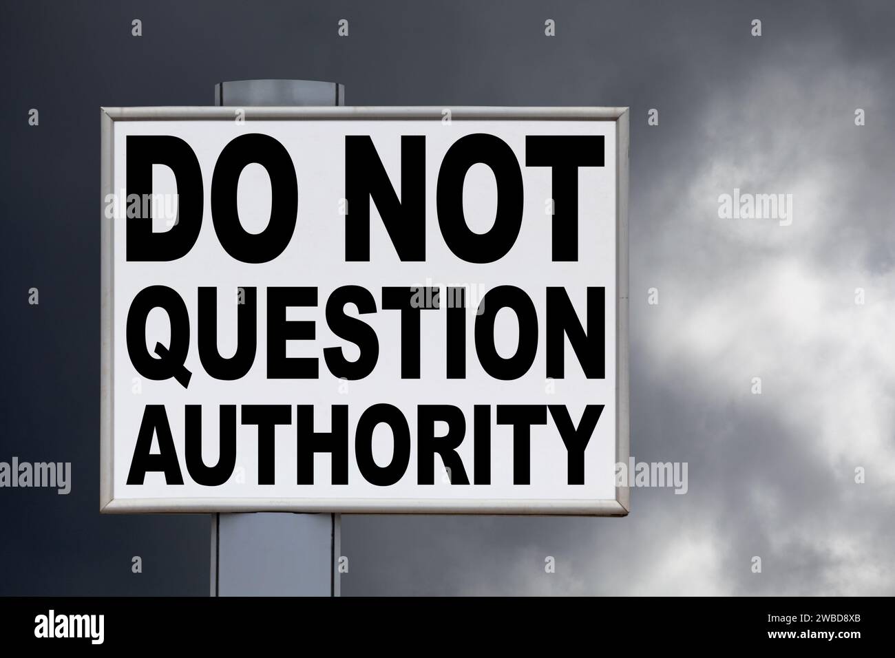 Gros plan sur un panneau d'affichage blanc contre un ciel menaçant avec le message "ne pas remettre en question l'autorité" écrit au milieu. Banque D'Images Gros plan sur un panneau d'affichage blanc contre un ciel menaçant avec le message "ne pas remettre en question l'autorité" écrit au milieu. Banque D'Images