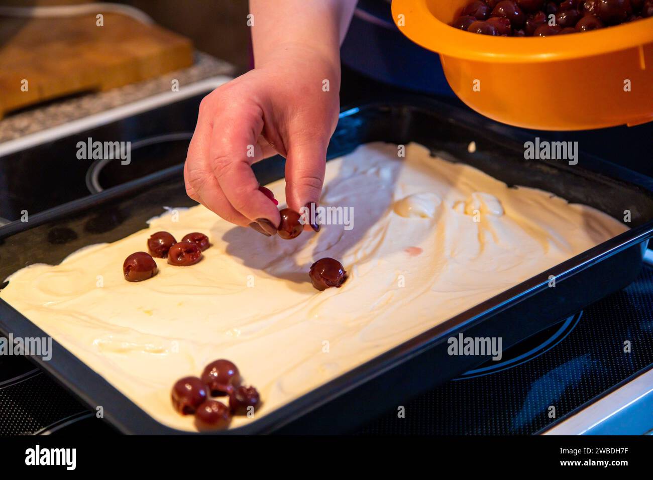 Kirschen auf Kuchenblech und Teig verteilen Banque D'Images