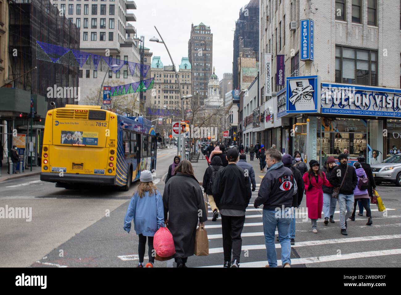 Un autobus scolaire jaune qui descend une rue à côté d'un groupe de personnes à New York, aux États-Unis Banque D'Images