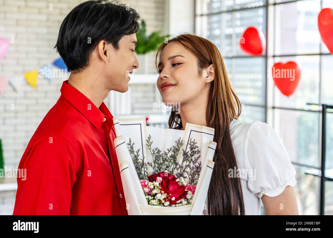 Un jeune homme présentant un bouquet de fleurs à une belle femme Banque D'Images