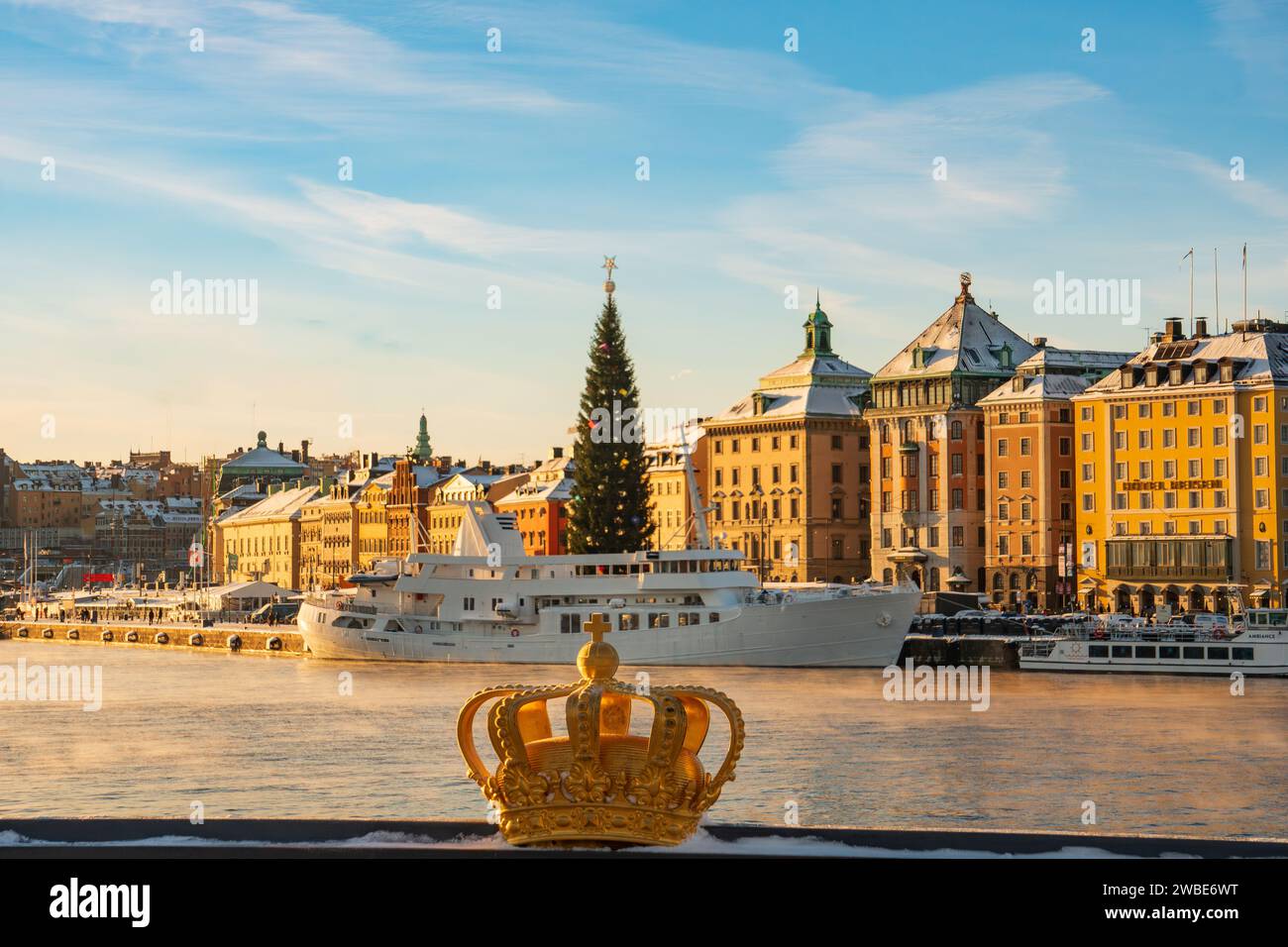 Le symbole de la couronne royale de la Suède, sur le pont Skeppsholmen, surplombant la vieille ville et le sapin de noël, par une froide journée d'hiver ensoleillée, neige. Banque D'Images