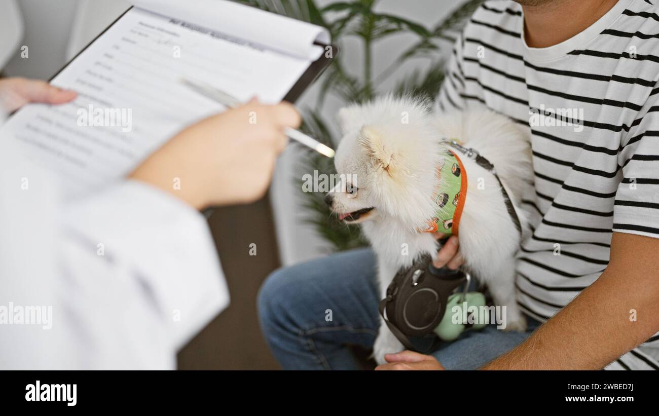 Anxieux jeune homme caucasien assis patiemment avec son chien de compagnie bien-aimé dans la salle d'attente pour une consultation vétérinaire à la clinique vétérinaire. Banque D'Images