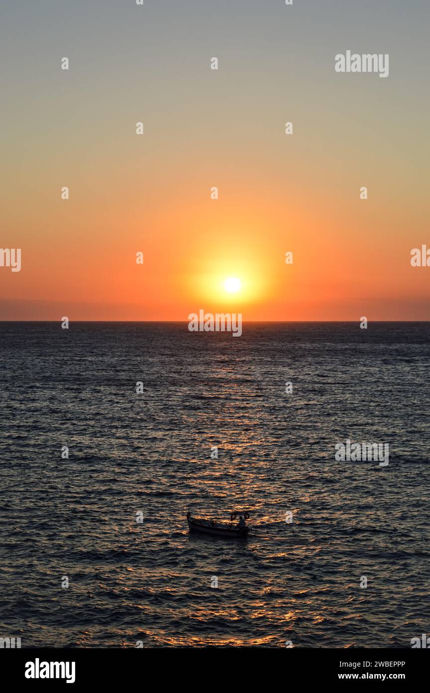 Un pêcheur naviguant vers le soleil au coucher du soleil. La photo est prise sur l'île grecque de Serifos. Banque D'Images