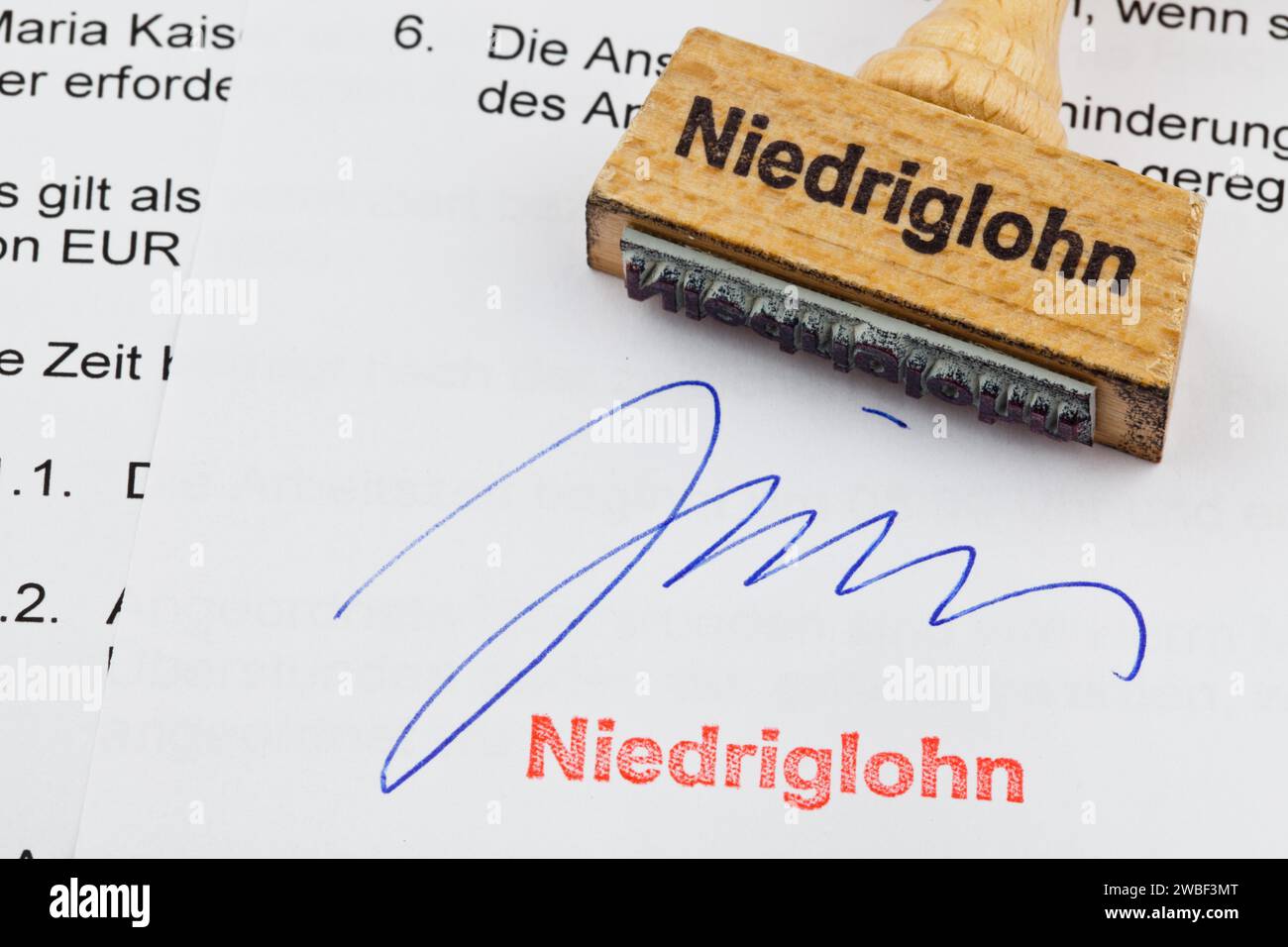 Un tampon en bois se trouve sur un document. Inscription allemande : bas salaire Banque D'Images