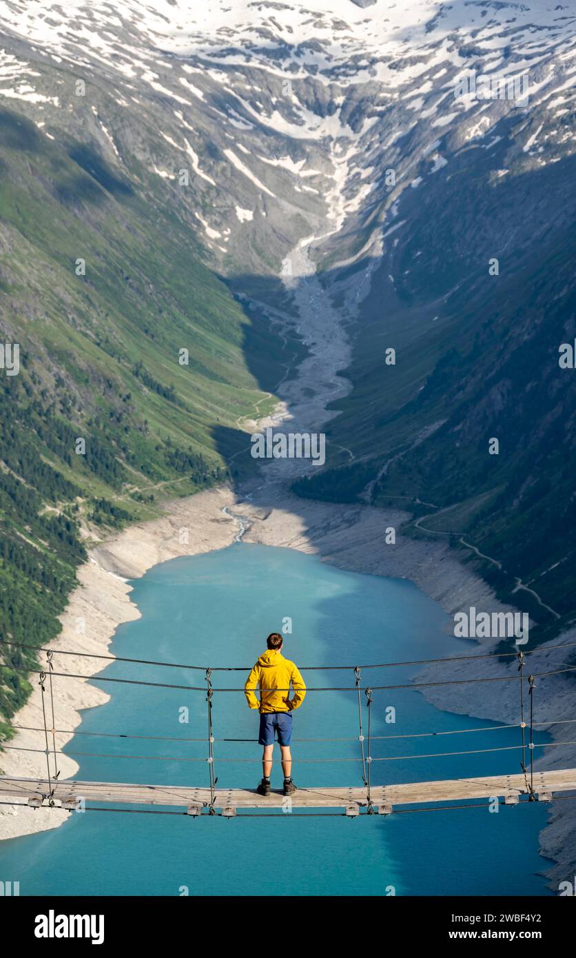 Alpinistes sur un pont suspendu, paysage montagneux pittoresque près de l'Olpererhuette, vue sur le lac bleu turquoise Schlegeisspeicher, Berliner Banque D'Images