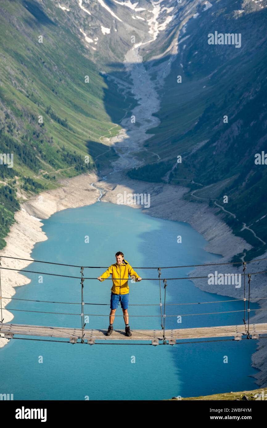 Alpinistes sur un pont suspendu, paysage montagneux pittoresque près de l'Olpererhuette, vue sur le lac bleu turquoise Schlegeisspeicher, Berliner Banque D'Images