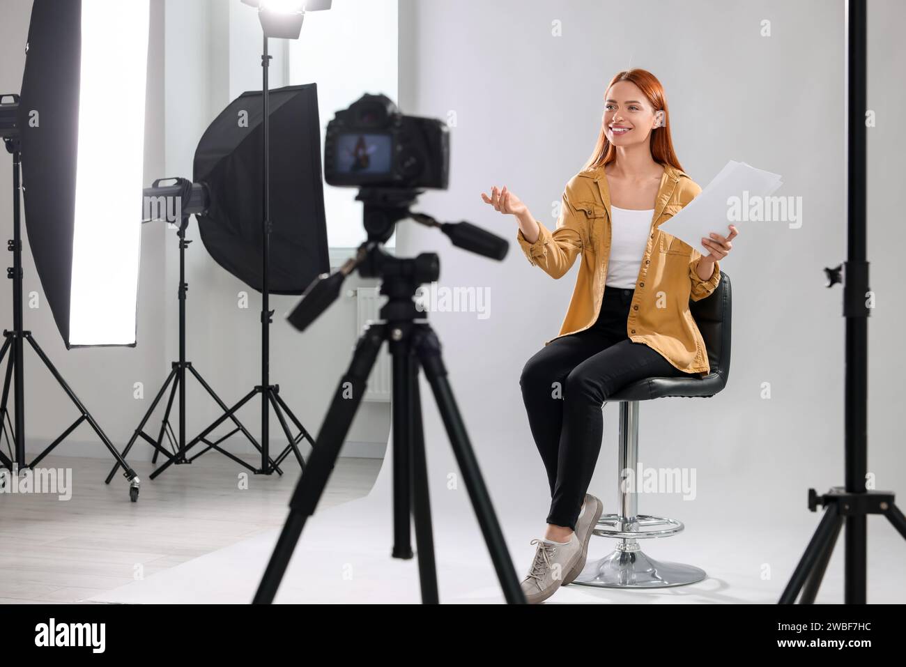 Appel de casting. Femme avec script jouant devant la caméra sur fond gris clair au studio Banque D'Images