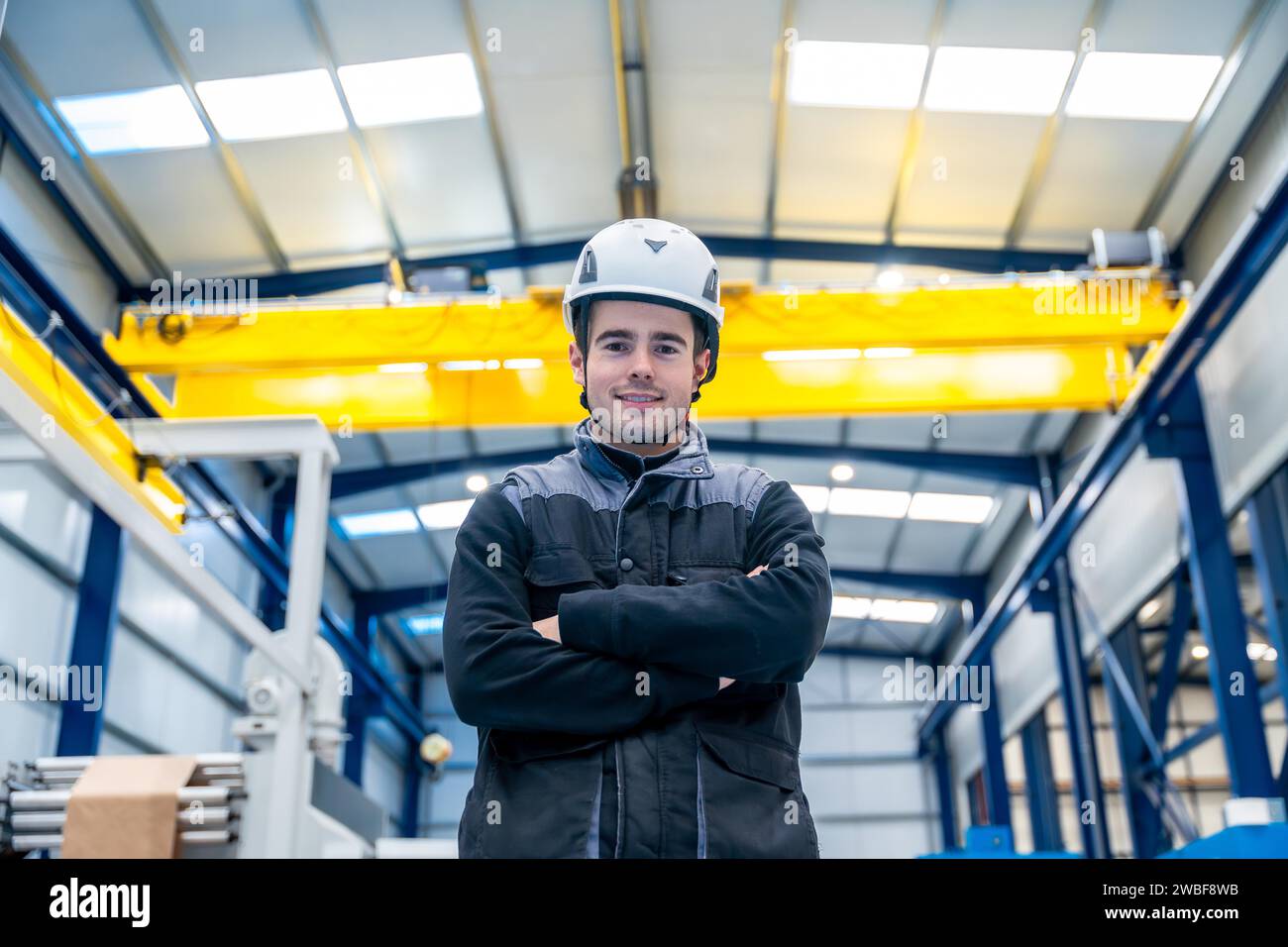 Portrait d'un ouvrier manuel masculin avec casque debout fièrement dans une usine Banque D'Images